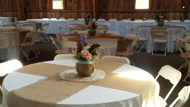 centerpieces made from a burlap covered bubble bowl with babys breath, pink spray roses, blue hydrangeas, and burgundy grass plumes