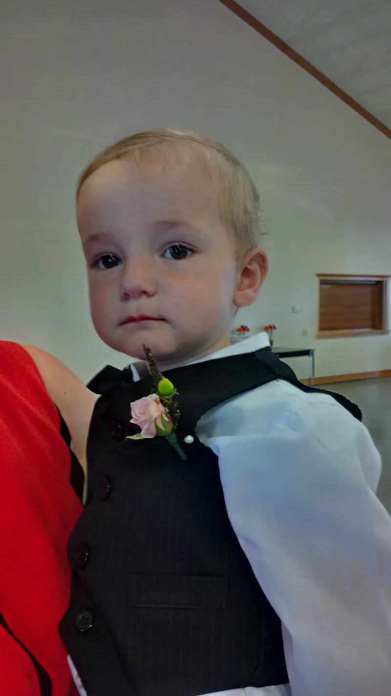 tiny pink spray rose bud boutonniere for a toddler boy.
