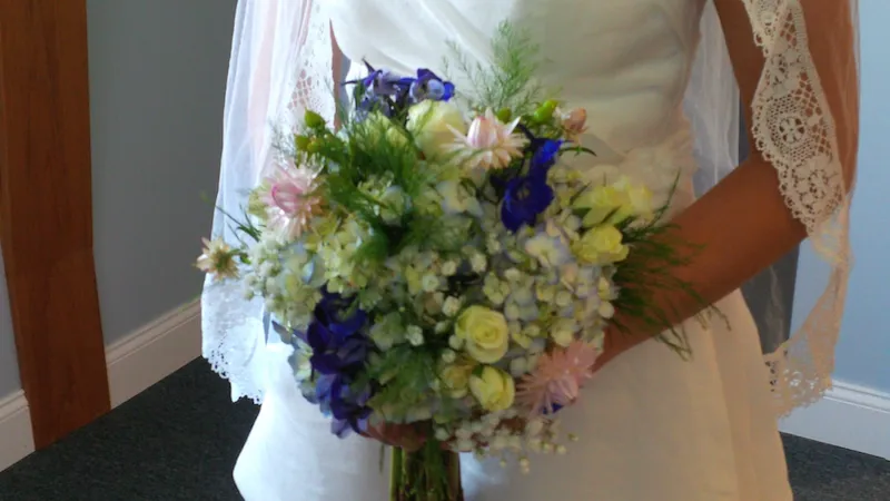 bridal bouquet with white and baby blue hydrangeas with a touch of deep blue delphinium and soft pink spray rose flowers.